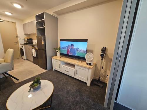 a living room with a flat screen tv on a table at Cityscape Retreat - Apartment with Pool and Gym in Auckland
