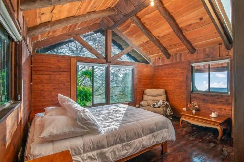 a bedroom with a bed in a room with windows at Cabin in the Clouds in Tapantí