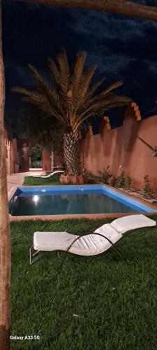 a pool with a chaise lounge next to a palm tree at Chez Kossai Atlas Farm in Chtawna