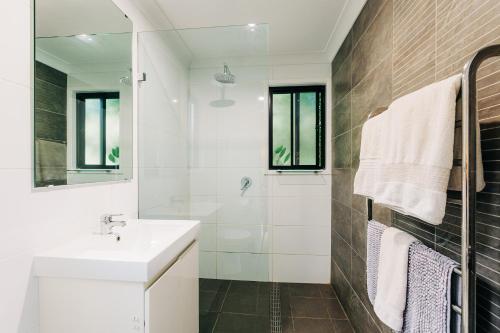 a white bathroom with a sink and a shower at Mystwood Spa Cabins in Wollombi