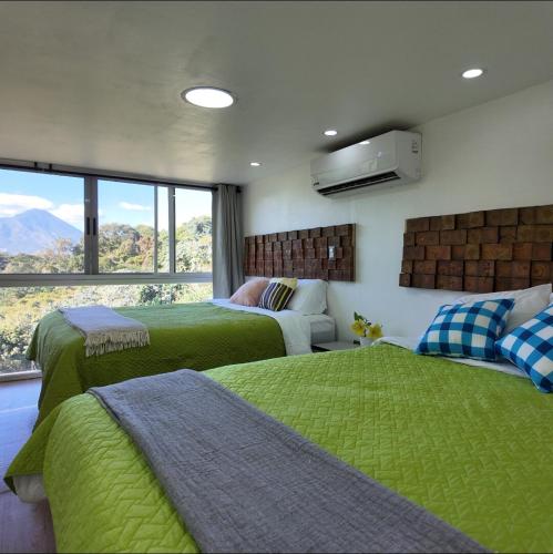 a bedroom with two beds with green sheets and a window at Las Terrazas Suites Studio Apartment in San Salvador