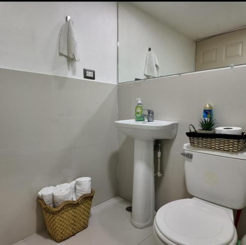 a white bathroom with a toilet and a sink at Las Terrazas Suites Studio Apartment in San Salvador