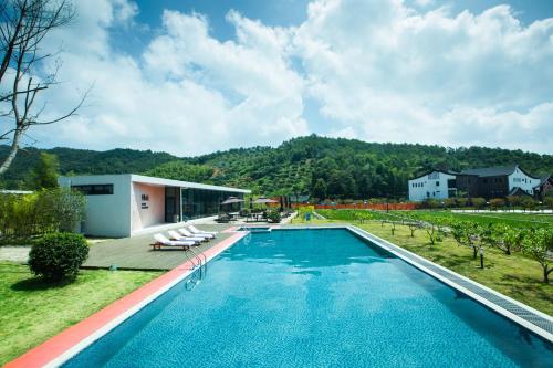 a swimming pool with chairs and a house at Dongqian Lake Junlan Resort Hotel in Ningbo