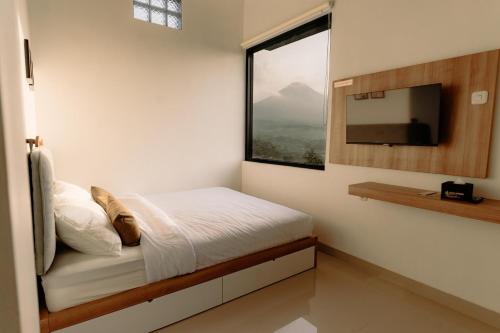 a bedroom with a bed with a window and a tv at SALU AMAANA Residence Syariah in Wonosobo