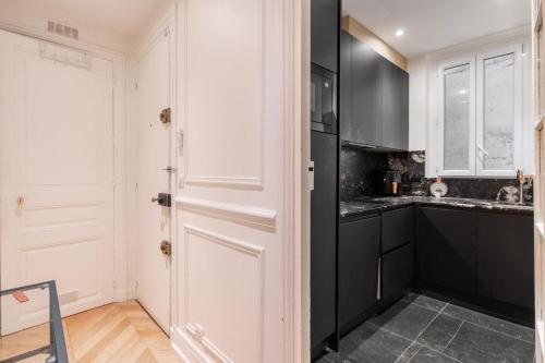 une cuisine avec des armoires noires et une porte blanche dans l'établissement Luxury Flat Montorgueil Le Marais Paris, à Paris