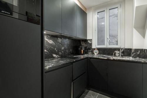 une cuisine avec des armoires noires et une fenêtre dans l'établissement Luxury Flat Montorgueil Le Marais Paris, à Paris