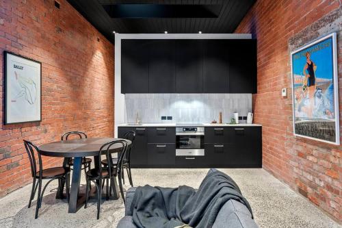 a kitchen with a table and a brick wall at The Milliner on Elizabeth in Geelong West