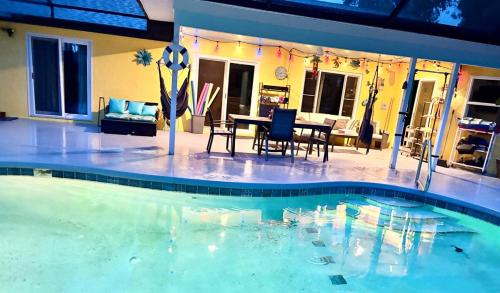 a swimming pool with a table and chairs in a house at 10 Min from Beach, Private Pool with Lanai Palm Coast Family Home in Palm Coast