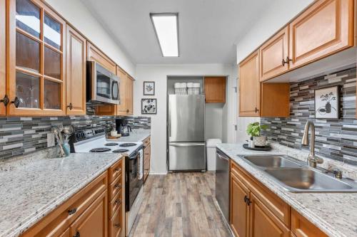 a kitchen with wooden cabinets and a stainless steel refrigerator at The Duke Retreat Close to Duke & Downtown Villa in Durham