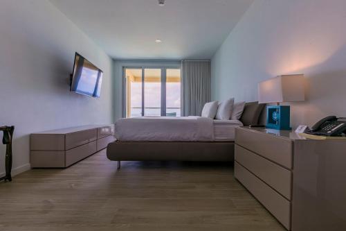 a bedroom with a bed and a desk with a telephone at Azure Beach Residences in Palm-Eagle Beach