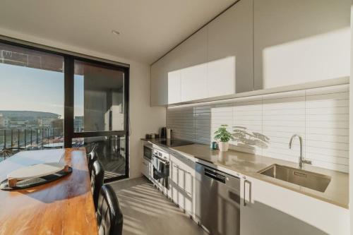 a kitchen with a table and a large window at Tuam St Stay - 1BR with Balcony Bath in Christchurch