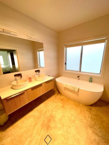 a bathroom with two sinks and a tub and a window at Straun Street House in Naracoorte