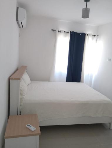 a bed in a room with two windows at Ligas Mayores Residence in Boca Chica