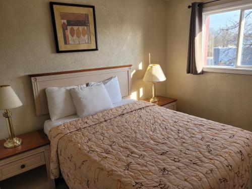 a bedroom with a bed and two lamps and a window at Sand Castle Suites Motel in Port Elgin