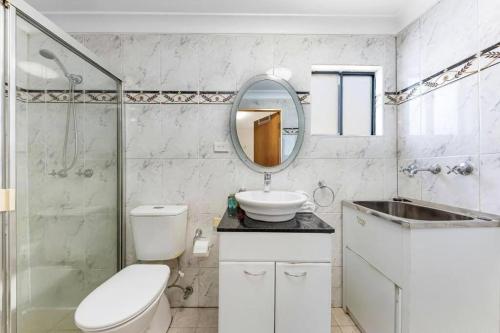 a bathroom with a toilet and a sink and a mirror at Cheerful Two Bedroom house in Sydney