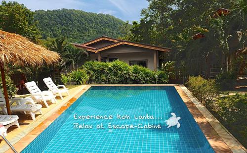 a swimming pool with chairs and a house at Escape-Cabins in Ko Lanta