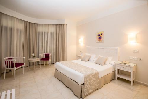 a hotel room with a bed and a table and chairs at Gran Sol in Zahara de los Atunes