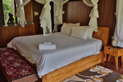 a bedroom with a large bed with white sheets at Umah D Meranggi in Banjarangkan