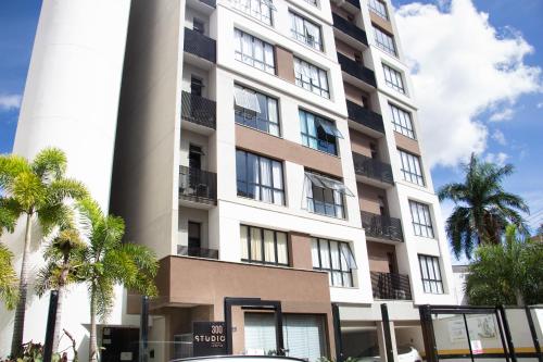 a tall building with palm trees in front of it at Apartamento Loft Lazer Completo in Belo Horizonte