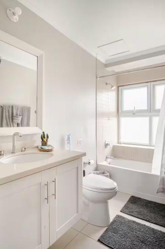 a white bathroom with a toilet and a tub and a sink at Ocho Rios Ocean Escape in Richmond