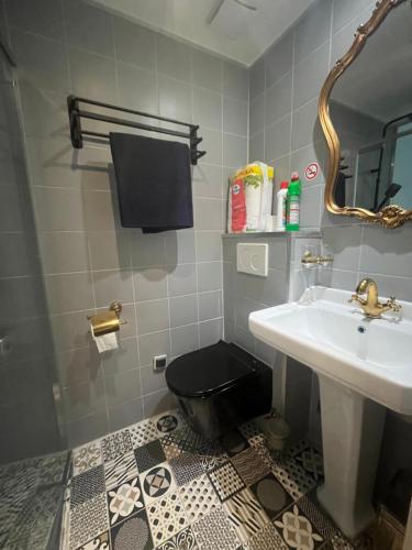La salle de bains est pourvue de toilettes noires et d'un lavabo. dans l'établissement Petit Dupleix atypique Porte Maillot F3, à Paris