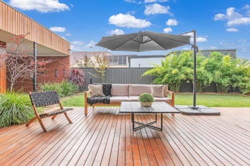 patio con divano e ombrellone di Villa Simone - Tranquil Hideaway in the Heart of Echuca a Echuca