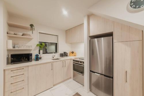a kitchen with wooden cabinets and a stainless steel refrigerator at 2BR Stay in the City Free Wi-Fi - Gloucester in Christchurch
