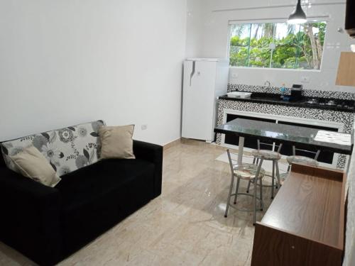 a living room with a black couch and a kitchen at Apartamento na Praia de Pontal do Sul- Pontal do Paraná in Pontal do Paraná