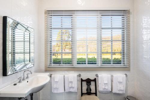a white bathroom with a sink and a window at Lake David Luxury Lakehouse in Kangaroo Valley