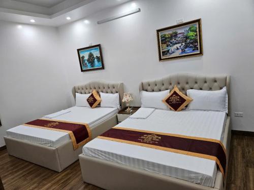 two beds in a room with white walls at Hoàng Gia Hotel Royal in Kim Bảng