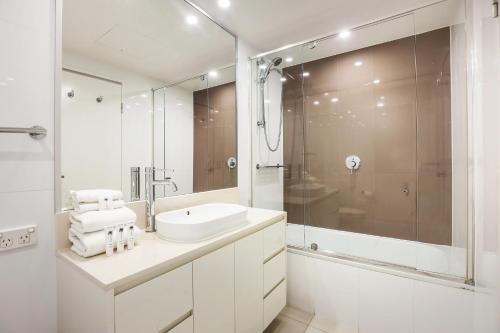 a white bathroom with a sink and a shower at Number 1 H Residences - WiFi, Parking & More by Gold Coast Holidays in Gold Coast