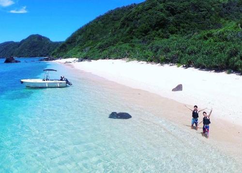 two children standing on a beach with a boat at amami 星空テラス in Akaoki