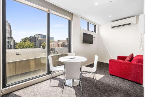 a room with a table and chairs and a red couch at Comfort Apartments Box Hill in Box Hill