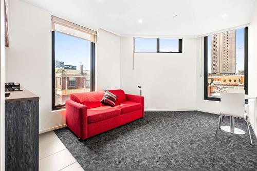 a red couch in a room with a window at Comfort Apartments Box Hill in Box Hill