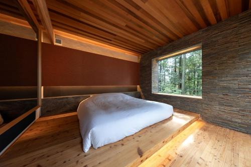 a bedroom with a white bed in a room with a window at 奥武雄温泉　風の森 in Ureshino