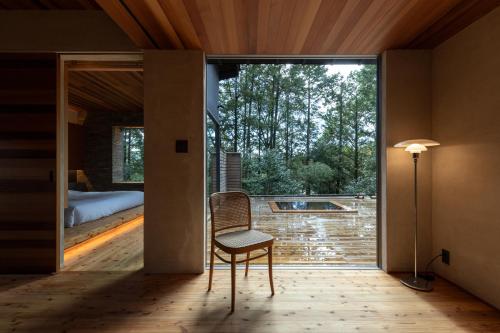 a room with a chair and a sliding glass door at 奥武雄温泉　風の森 in Ureshino