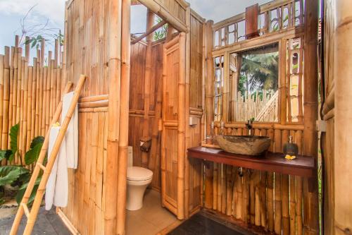 a wooden bathroom with a toilet and a window at TUJUH Angel by GenuineHost in Ubud