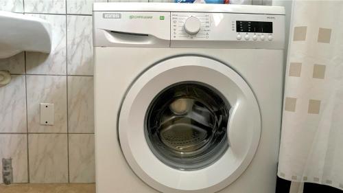 a white washing machine sitting in a bathroom at Central - Gated - 2 Bedrooms - Near Beaches in Julianadorp