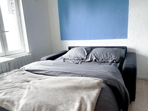 Ce lit se trouve dans une chambre dotée d'un mur bleu. dans l'établissement Studio cosy, à Valenciennes