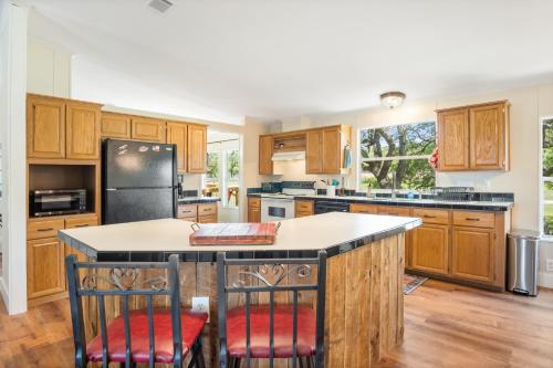 a kitchen with wooden cabinets and a black refrigerator at Tejas Hills of Pipe Creek in Pipe Creek