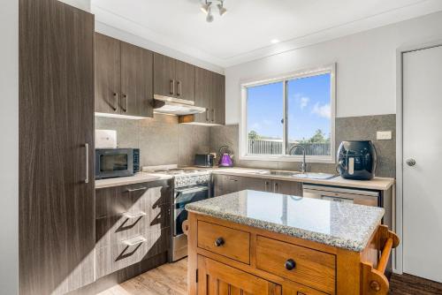 a kitchen with wooden cabinets and a counter top at Kew Golf Shack in Kew