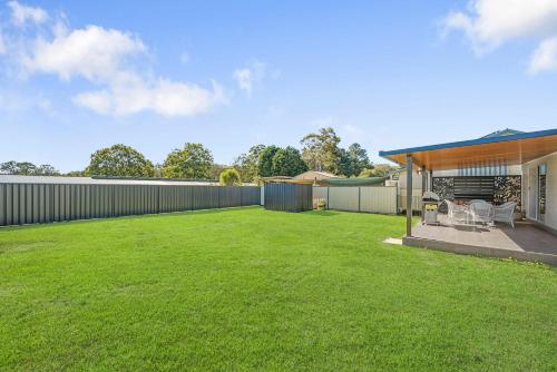 a backyard with a fence and a grass yard at Kew Golf Shack in Kew