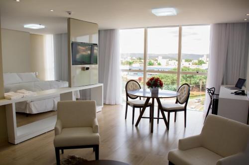 a living room with a table and chairs and a bedroom at Select Hotel in Palmas