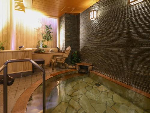 a hot tub in a room with a brick wall at Dormy Inn Sapporo Annex in Sapporo