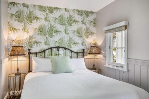 a bedroom with a bed with a tropical wallpaper at Cottage 2 Hyams Beach Seaside Cottages in Hyams Beach