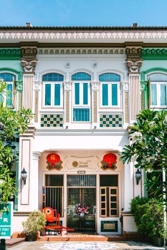 a large white building with blue windows and red chairs at O'nya Phuket Hotel in Phuket