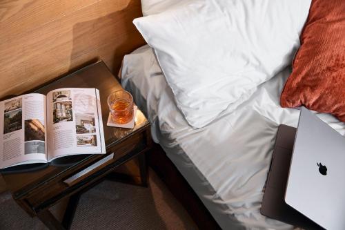 a bed with an open book on a night stand next to a side table at Harbour Rocks by Ode Hotels in Sydney