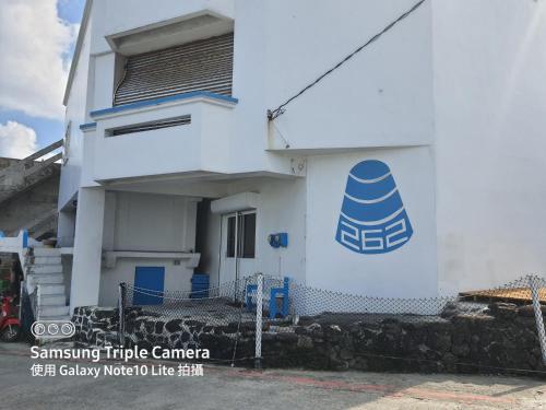a white building with a blue sign on it at 蘭嶼 262 民宿 in Lanyu