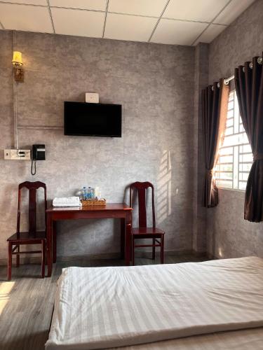 a bedroom with a bed and a desk with two chairs at Trung Hau Hotel in Can Tho