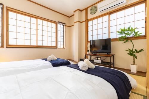2 Betten in einem Zimmer mit Fenstern und einem TV in der Unterkunft Cozy condo for 2 PPL near Teradacho Sta 4 min walk cecilia301 in Osaka